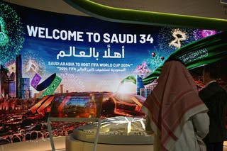 People walk past a stall displaying a welcome message for the Saudi 2034 FIFA World Cup football tournament at the Ministry of Media in Riyadh on May 13